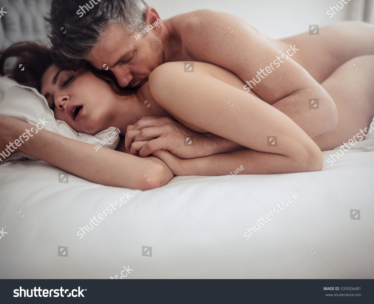 An naked woman kissing another naked woman